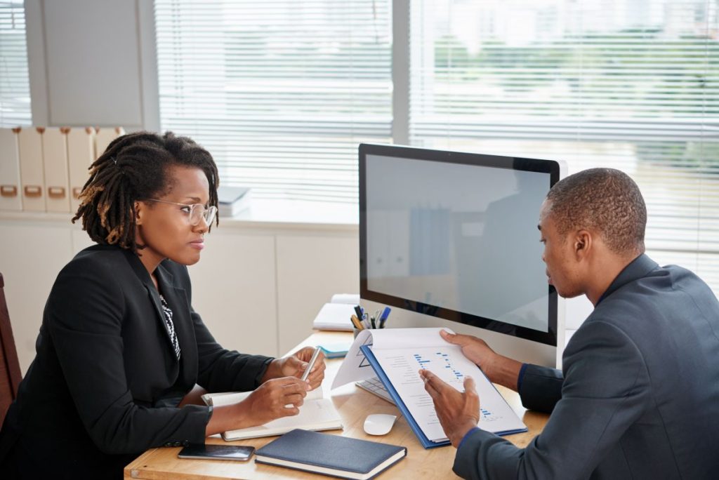 afro american man suit holding documents talking female boss